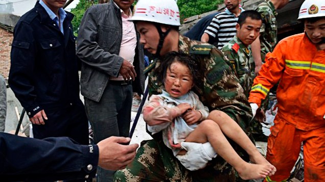 Equipe de resgate socorre criança na província chinesa de Sichuan neste sábado, após terremoto que deixou mais de 150 mortos
