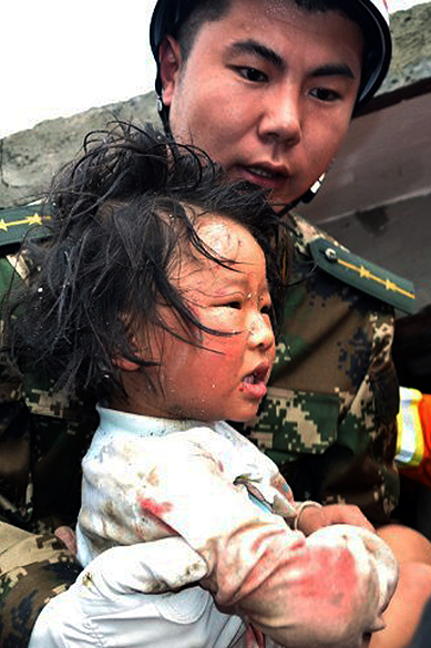 Equipe de resgate socorre criança na província chinesa de Sichuan neste sábado, após terremoto que deixou mais de 150 mortos