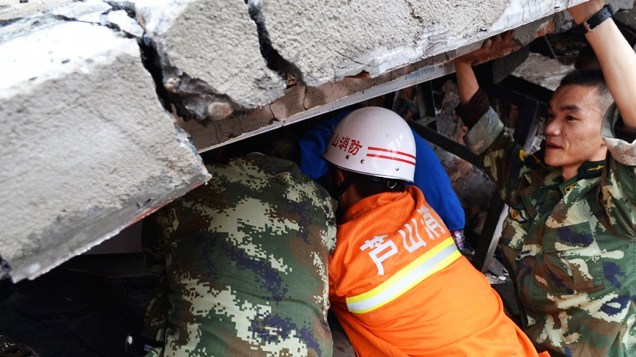 Homens resgatam criança dos destroços após um terremoto ter atingido a província central chinesa de Sichuan neste sábado