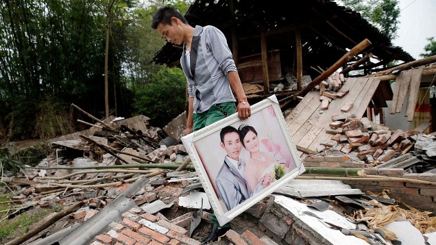 Homem recolhe foto de seu casamento de sua casa, destruída pelo terremoto
