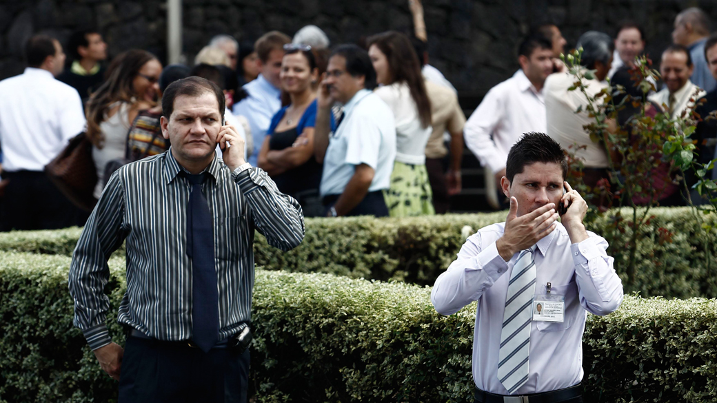 Pessoas falam em seus celulares depois de serem evacuadas de prédios após um terremoto em San Jose, Costa Rica