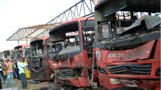 Pessoas observam os ônibus queimados após explosão de uma bomba em terminal na Nigéria