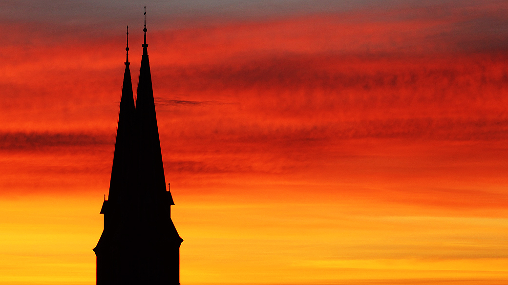 Torres da igreja Familienkirche têm silhueta destacada durante amanhecer em Viena