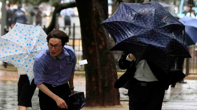 Pedestres se protegem com guarda-chuvas de vento forte e chuva causada pelo tufão Bolaven em Seul