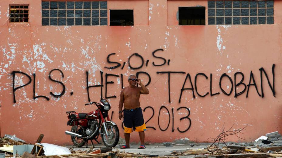Filipino em frente a frase S.O.S, por favor ajudem Tacloban