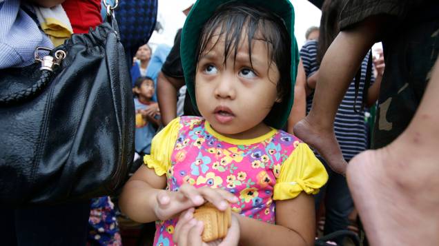 Menina recebe bolachas enquanto espera para embarcar para Manila, nas Filipinas