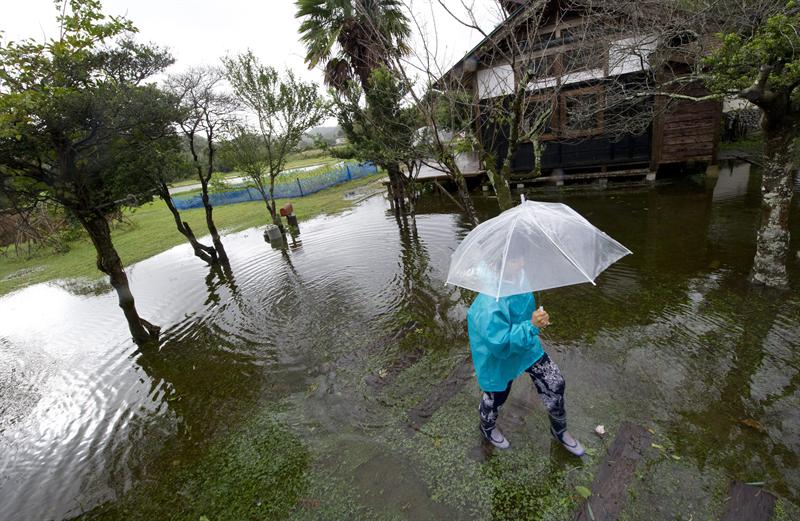 Mulher caminha em área inundada pelo tufão Wipha