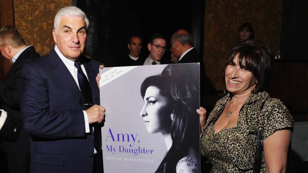 Pais de Amy, Mitch e Janis Winehouse, seguram cartaz com a capa do livro escrito por Mitch
