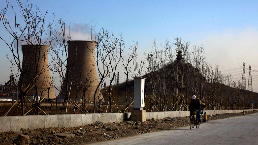 Ciclista passa próximo a usina termoelétrica em Pequim, na China – 22/11/2011