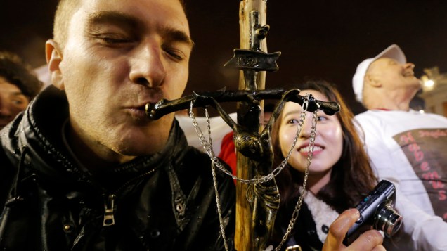 Fiél beija cruz após anuncio da escolha do novo papa, no Vaticano