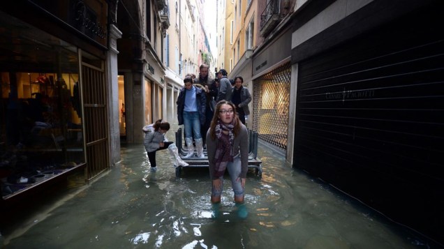 Venezianos e turistas se deslocam pela cidade inundada