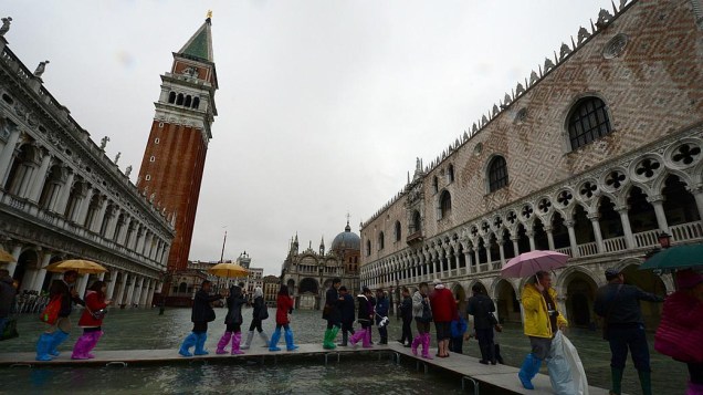 Venezianos e turistas se deslocam pela cidade inundada