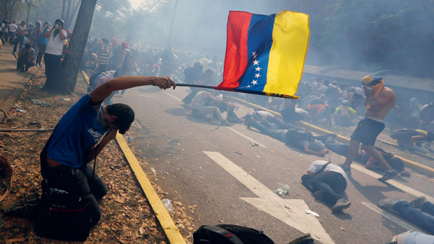 REPRESSÃO - Jovens tentam se proteger dos gases em ataque a passeata pacífica em Caracas, na quarta-feira 12