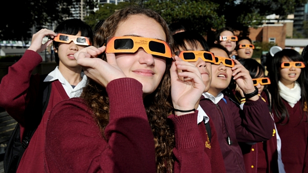 <p>Alunos de um colégio em Sidnei, Austrália, observam o fenômeno com óculos de proteção</p>