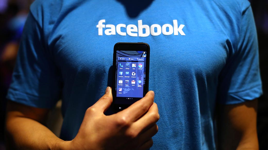Homem segura um celular com o programa do Facebook 'Home'