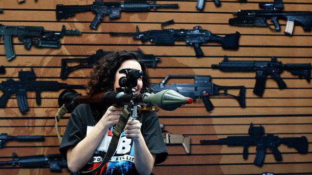 Uma mulher segura um lançador de granadas de brinquedo, durante a feira de games E3 de 2010