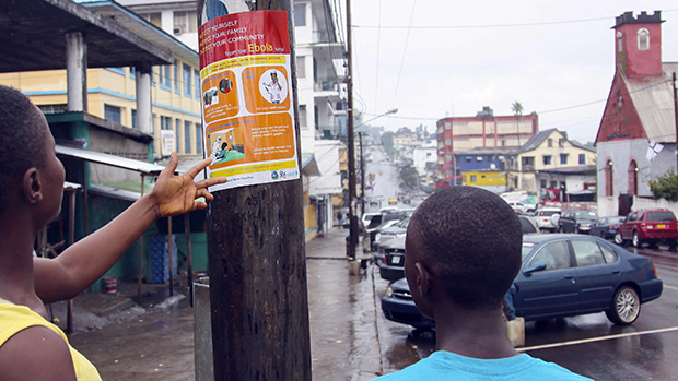 Na Libéria, homens leem um cartaz com informações sobre a prevenção do vírus Ebola, na cidade de Monróvia