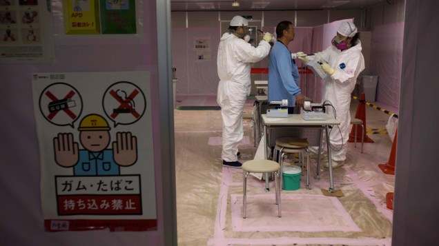 Trabalhador é examinado após entrar no centro de operações de emergência, do complexo nuclear de Fukushima, no Japão