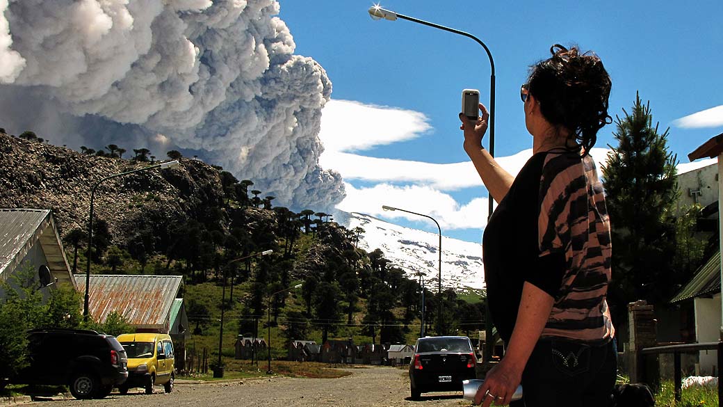Mulher observa o vulcão Copahue expelindo cinzas no Chile
