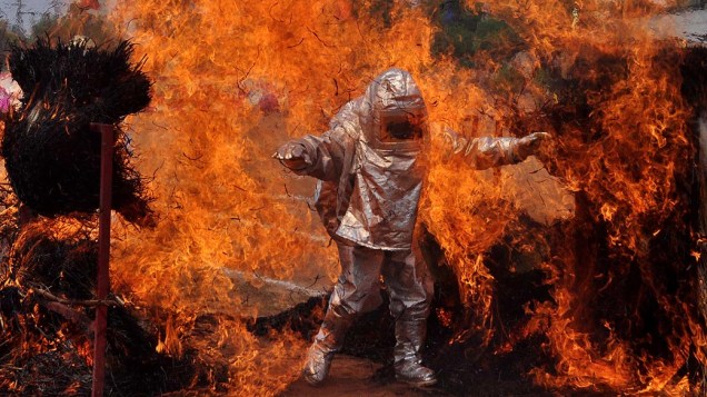 Bombeiro caminha por fogo usando roupa de proteção, na Índia