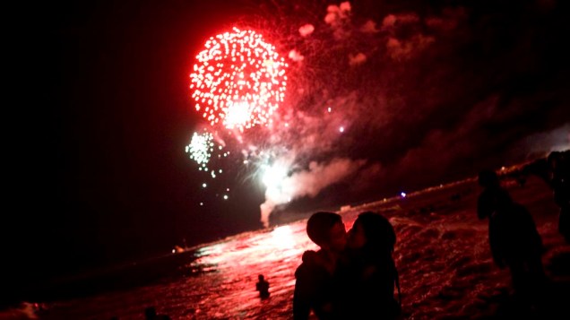 Pessoas observam a queima de fogos na praia de Málaga, na Espanha, para a tradicional festa de São João.