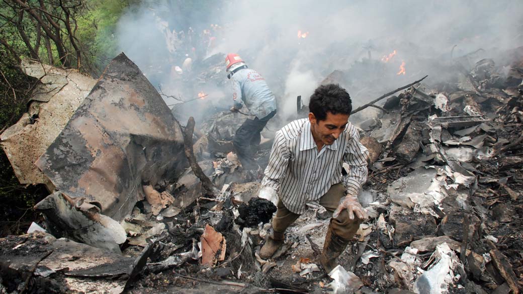 Pessoas trabalham na busca de vítimas após a queda de um avião em Islamabad, no norte do Paquistão. Com chuva pesada e visibilidade reduzida, a aeronave que transportava 152 pessoas caiu em uma floresta nos arredores da cidade, matando todos os passageiros a bordo