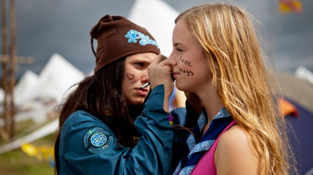 Jovens escoteiras pintam o rosto com a mensagem "Free Hugs" (Abraço Grátis), durante o 22º Acampamento Mundial Escoteiro