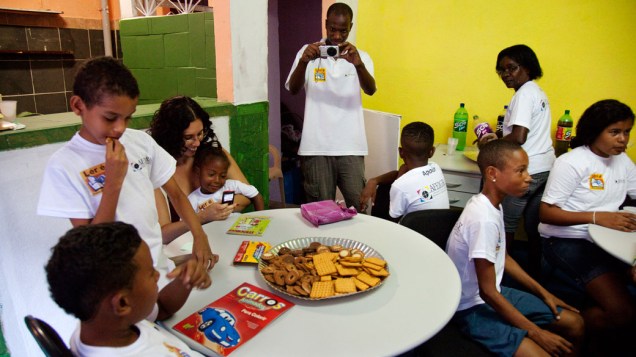 Otávio Cesar e crianças no ponto de leitura da comunidade Caracol, complexo da Penha, no Rio de Janeiro