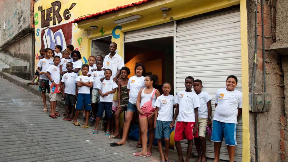 Otávio Cesar e crianças no ponto de leitura da comunidade Caracol, complexo da Penha, no Rio de Janeiro