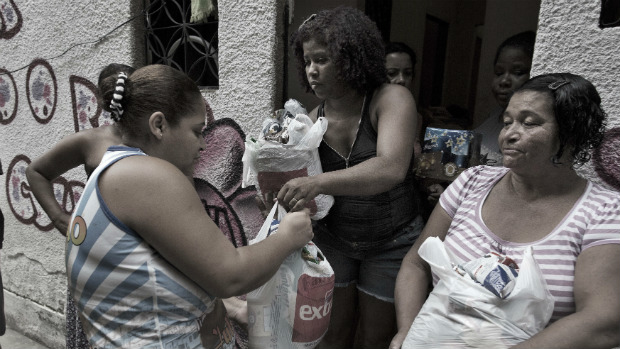 Claudineia Vasconcellos entrega sacolas com alimentos aos vizinhos, na favela de Acari