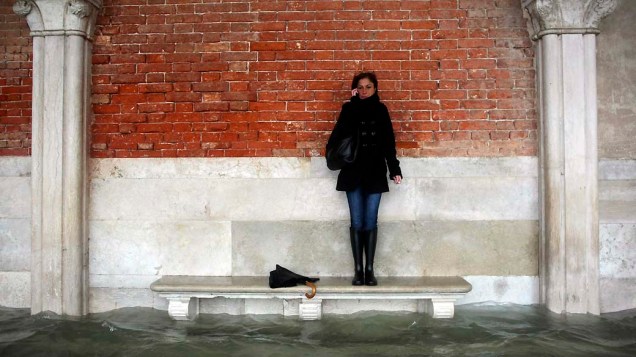 Mulher espera nível dàgua diminuir em Veneza