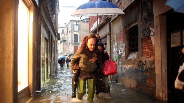 Pessoas caminham por rua alagada no período da Acqua Alta, na Itália