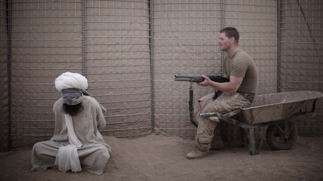Militar americano vigia afegão preso na província de Helmand, em abril