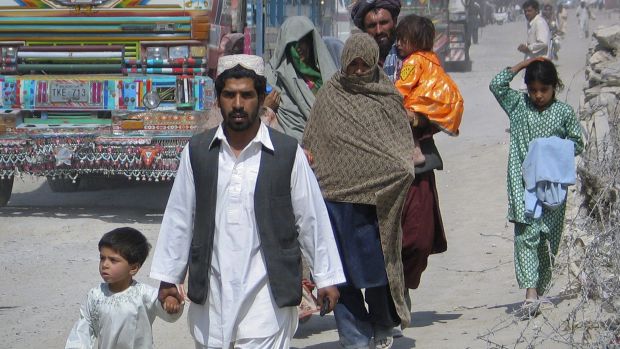 Homem cruza a fronteira do Paquistão em direção ao Afeganistão com seu filho. Foi nos campos de refugiados do Paquistão que cresceu a maioria dos novos recrutas do Talibã