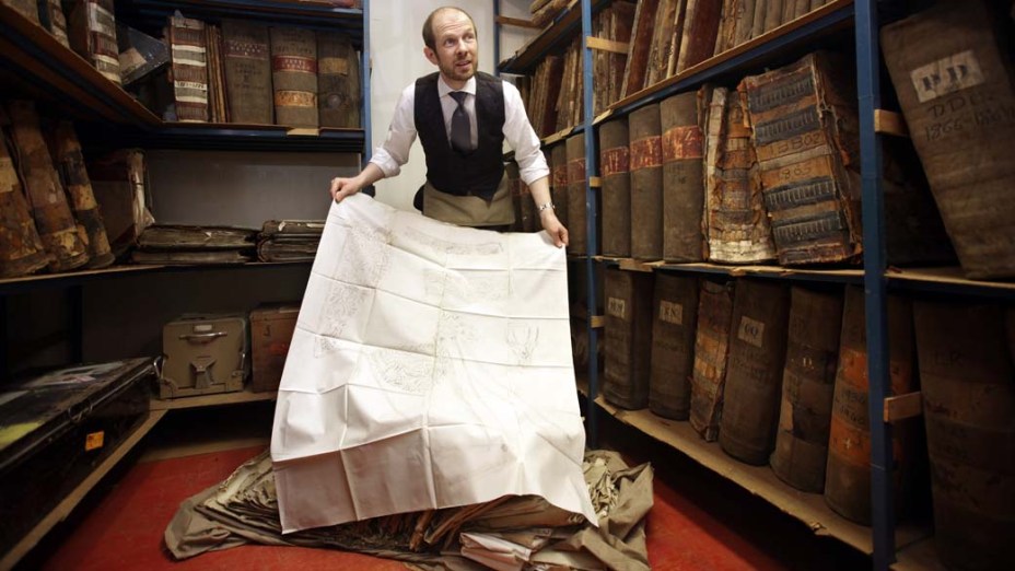 O gerente Keith Levett mostra gravuras de uniformes civis no arquivo da Henry Poole & Co, Londres