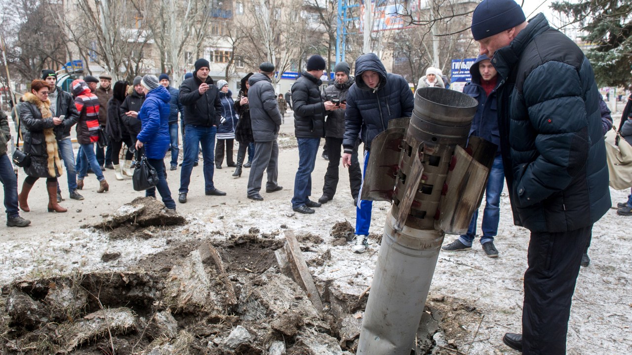 Pessoas observam um míssil embutido na rua após bombardeio em Kramatorsk, Ucrânia. Pelo menos seis policiais civis foram mortos e 21 feridos em um ataque com foguetes à um quartel-general