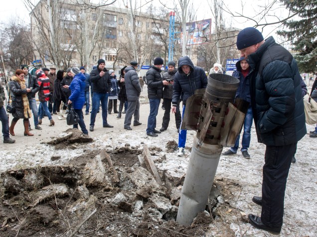Pessoas observam um míssil embutido na rua após bombardeio em Kramatorsk, Ucrânia. Pelo menos seis policiais civis foram mortos e 21 feridos em um ataque com foguetes à um quartel-general