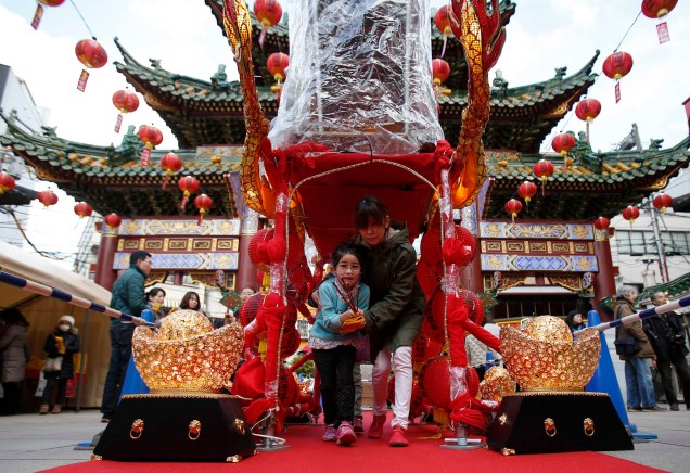 Em Chinatown, sul de Tóquio, mulher e menina caminham através de um santuário chinês em comemoração ao ano do Carneiro