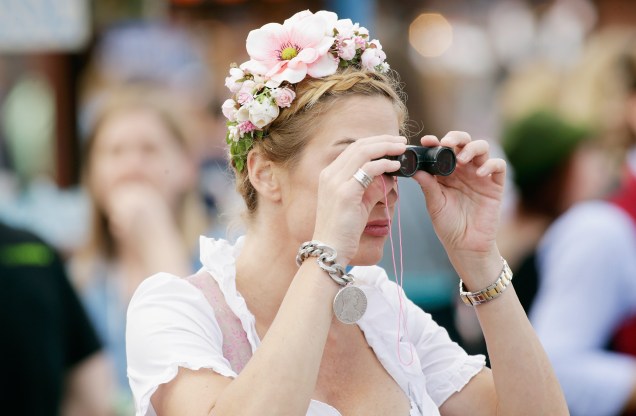 Uma mulher com trajes típicos da Alemanha assiste as apresentações do tradicional Oktoberfest através das lentes de um binóculo, em Munique, na Alemanha