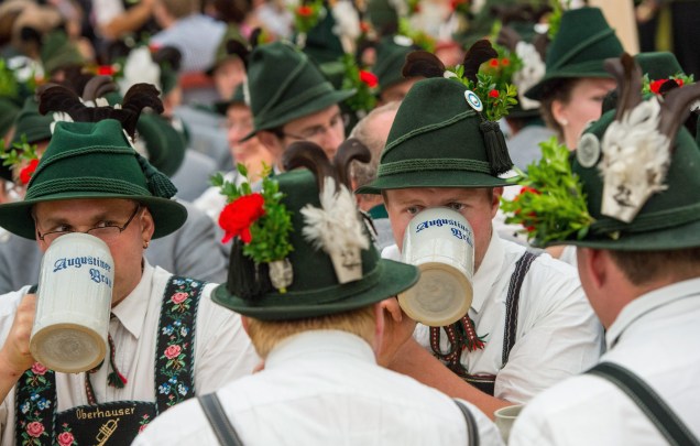 Na Alemanha, homens vestindo trajes tradicionais bebem cerveja após uma apresentação no festival Oktoberfest, em Munique