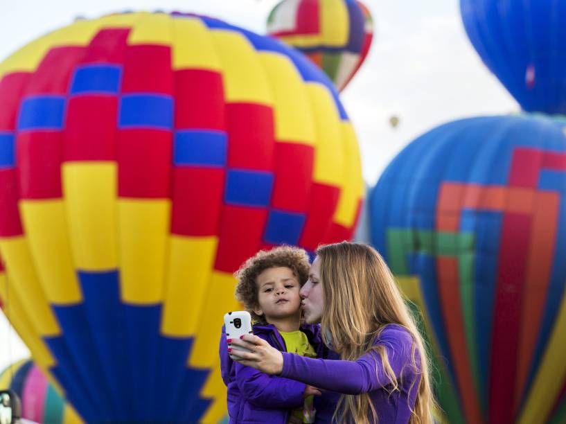 Mulher e criança tiram fotos em frente de balões que decolam durante o Festival Internacional de Balonismo de Albuquerque 2015