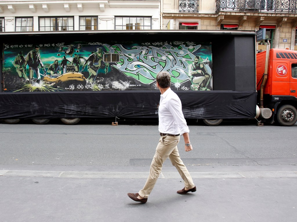 Pedestre observa obra de Banksy pintada em um caminhão