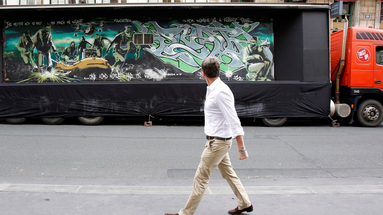 Pedestre observa obra de Banksy pintada em um caminhão