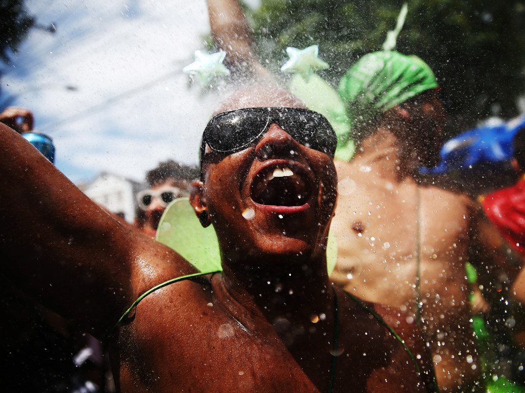 Folião se refresca com água jogada durante desfile do bloco de rua "Céu na Terra", no Rio de Janeiro