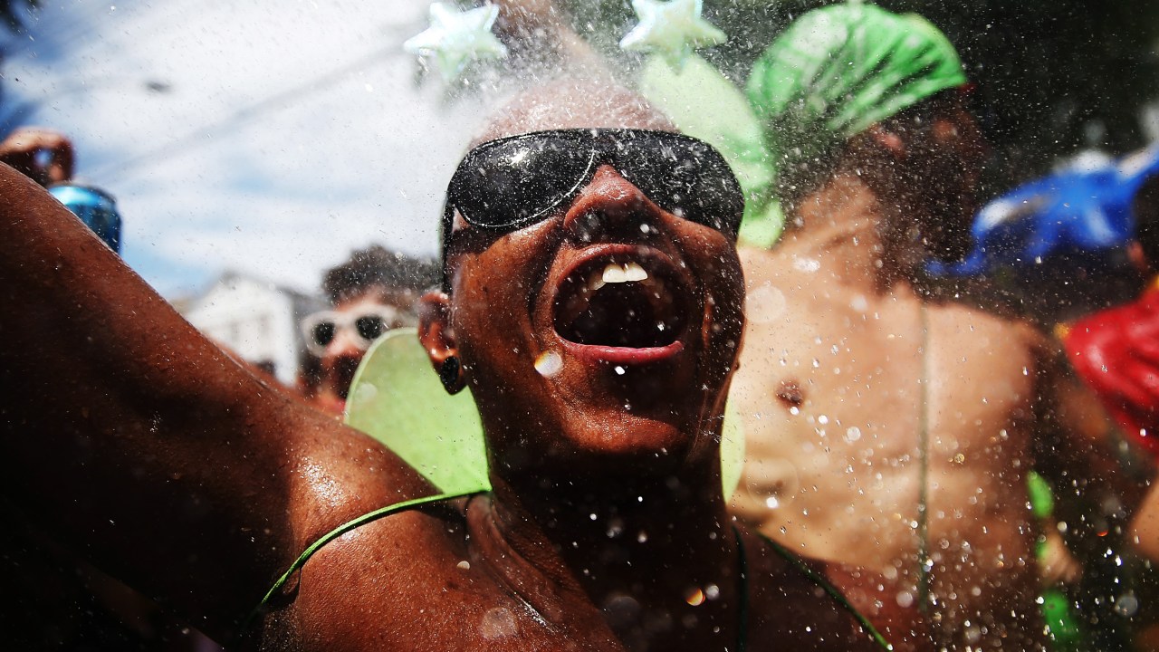 Folião se refresca com água jogada durante desfile do bloco de rua "Céu na Terra", no Rio de Janeiro