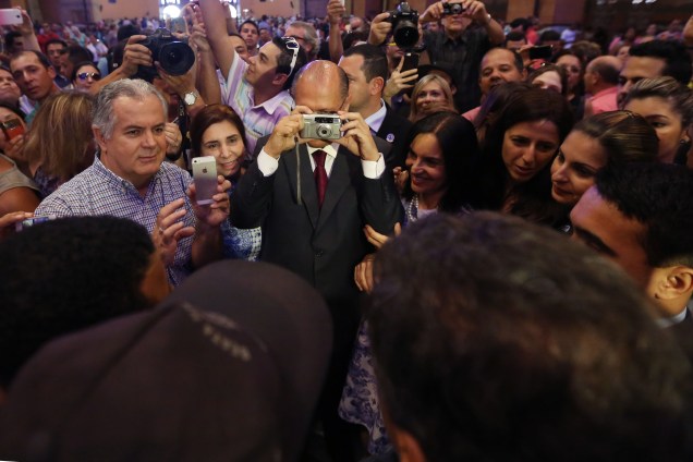O governador de São Paulo, Geraldo Alckmin, vira fotógrafo e tira uma foto de Aécio Neves com uma fã, em Aparecida