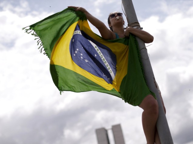 Manifestante segura uma bandeira do Brasil durante protesto pedindo o impeachment da presidente Dilma Rousseff, nos arredores do Congresso Nacional, em Brasília (DF) - 13/12/2015