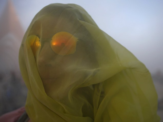 Mulher cobre o rosto com um lenço para se proteger de uma tempestade de areia durante o "Burning Man 2015: Carnaval de Espelhos". Cerca de 70.000 pessoas de todo o mundo se reúnem para passar a semana no deserto de Nevada durante o festival