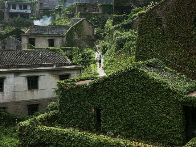Vegetação cobre quase totalmente as casas da aldeia abandonada de Houtouwan, na ilha de Shengshan, na China