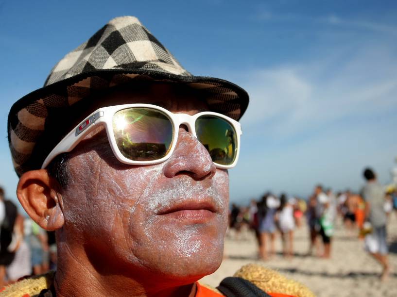 Homem de óculos de sol e protetor solar espalhado no rosto assiste a terceira etapa do Rio Pro 2015